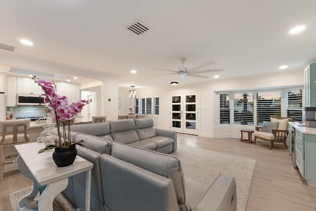 living area with a ceiling fan, recessed lighting, visible vents, and light wood finished floors