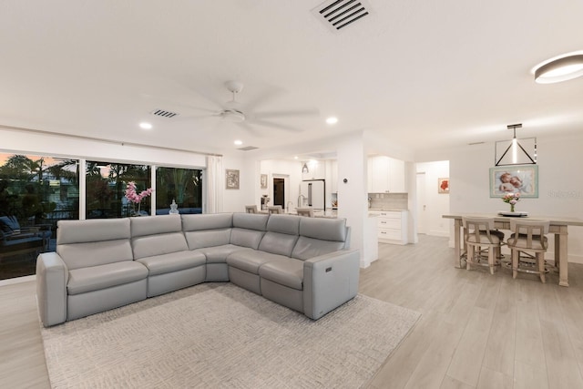 living room featuring a ceiling fan, light wood-type flooring, visible vents, and recessed lighting