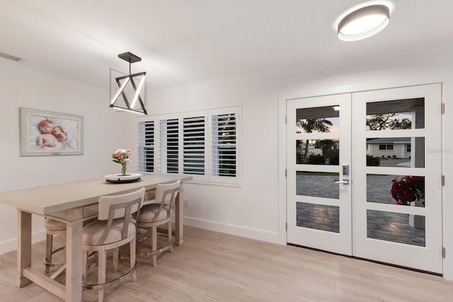 dining room featuring french doors, visible vents, light wood-style flooring, and baseboards