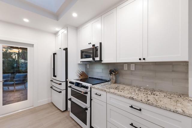 kitchen featuring decorative backsplash, premium appliances, light wood-style flooring, white cabinetry, and recessed lighting