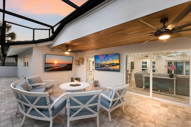 view of patio / terrace with glass enclosure, ceiling fan, and a fire pit