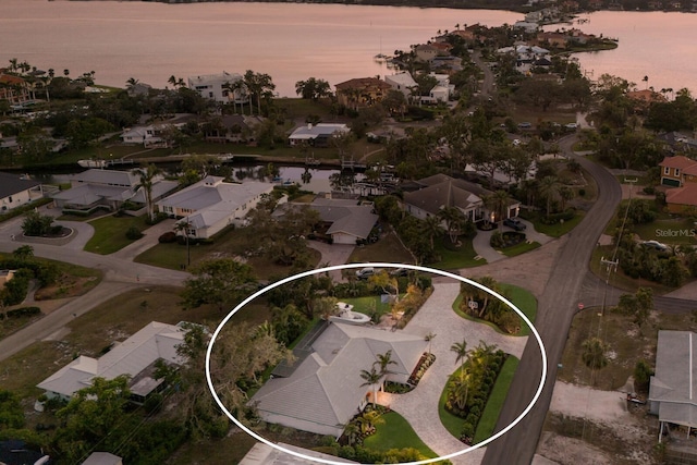 aerial view at dusk with a water view and a residential view