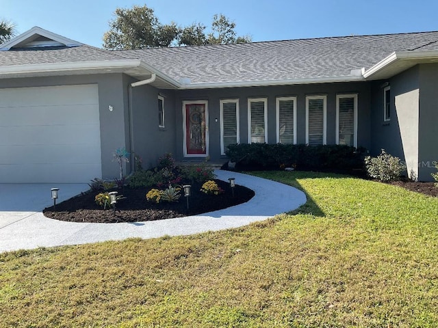 ranch-style home with stucco siding, an attached garage, a front yard, and roof with shingles