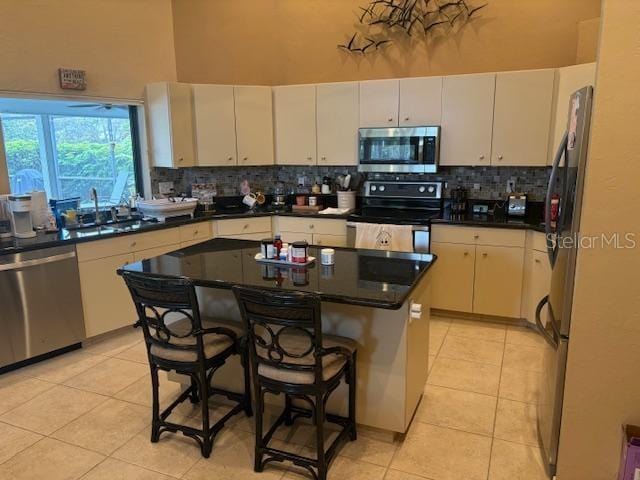 kitchen featuring backsplash, appliances with stainless steel finishes, a high ceiling, and a sink