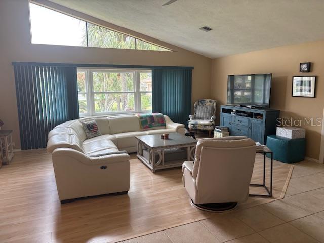 living area featuring visible vents, light wood-type flooring, and lofted ceiling