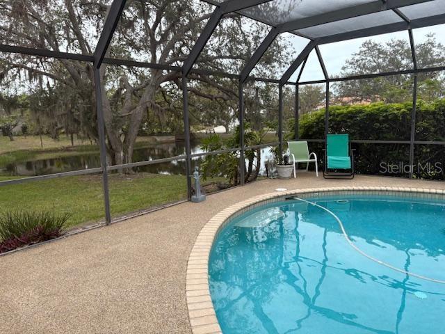 view of swimming pool featuring glass enclosure and a patio