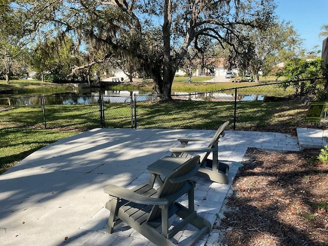 view of community with a patio area, a water view, a yard, and fence