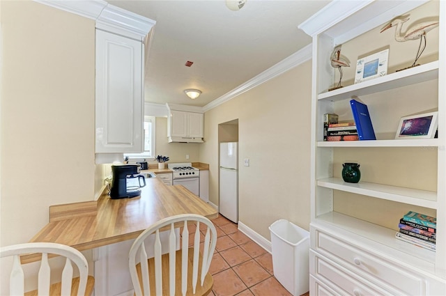 kitchen with white appliances, built in features, white cabinets, crown molding, and light tile patterned flooring