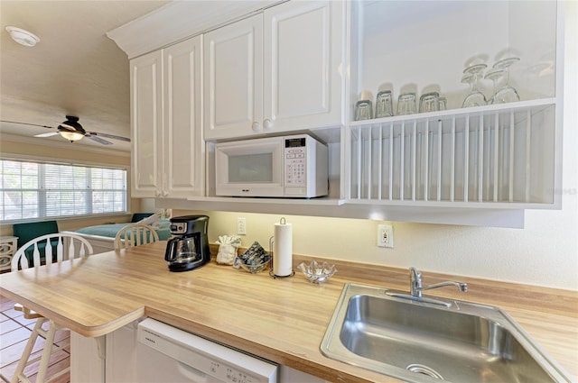 kitchen featuring white cabinetry, a sink, wood counters, ceiling fan, and white appliances