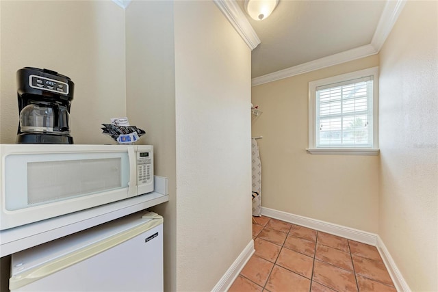 interior space featuring ornamental molding, light tile patterned flooring, and baseboards