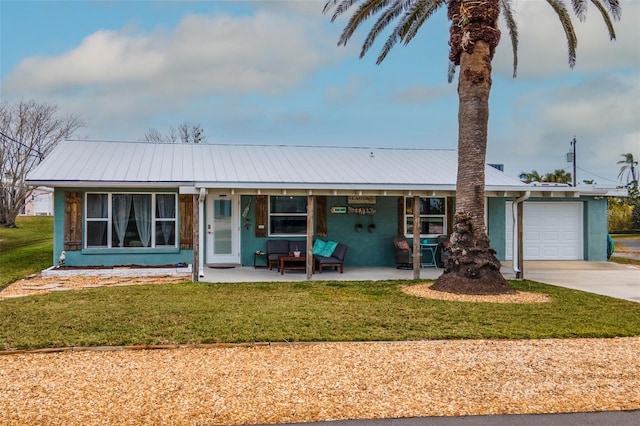 ranch-style home featuring metal roof, driveway, an attached garage, and a front lawn