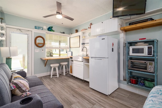 kitchen with open shelves, wood finished floors, white cabinets, white appliances, and a sink