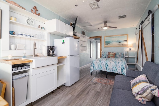 kitchen with open shelves, a barn door, a sink, and freestanding refrigerator