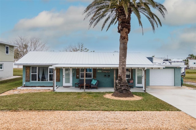 ranch-style house with a porch, concrete driveway, a front lawn, a garage, and metal roof