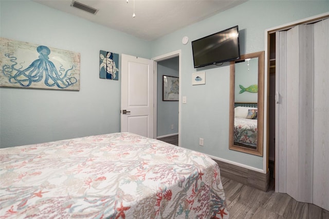 bedroom featuring visible vents, baseboards, a closet, and wood finished floors