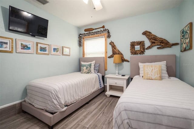 bedroom featuring visible vents, a ceiling fan, baseboards, and wood finished floors