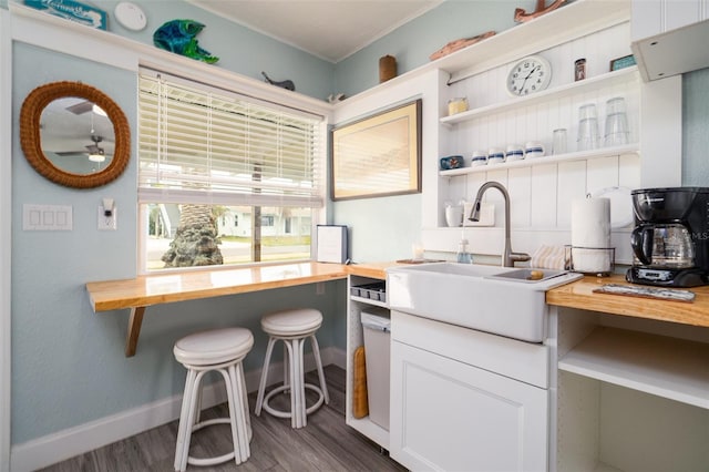 kitchen featuring a sink, open shelves, dark wood finished floors, white cabinets, and butcher block counters