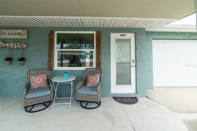 view of exterior entry with a porch, a garage, and stucco siding