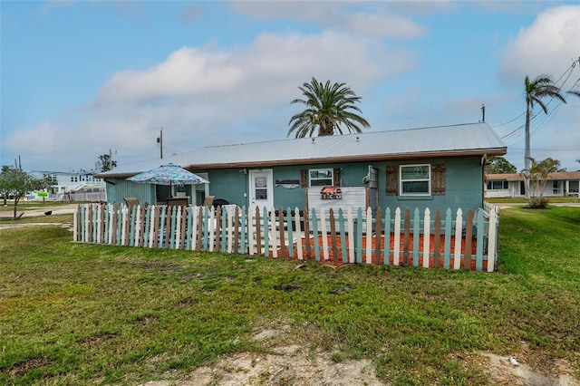 view of front facade with a front yard, fence, and metal roof