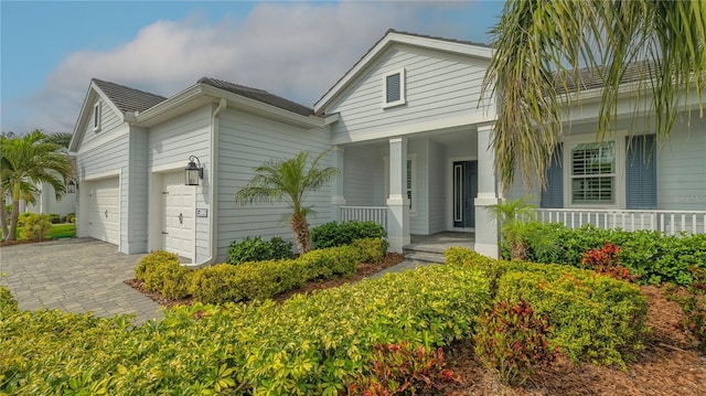 view of front facade with a porch, decorative driveway, and a garage