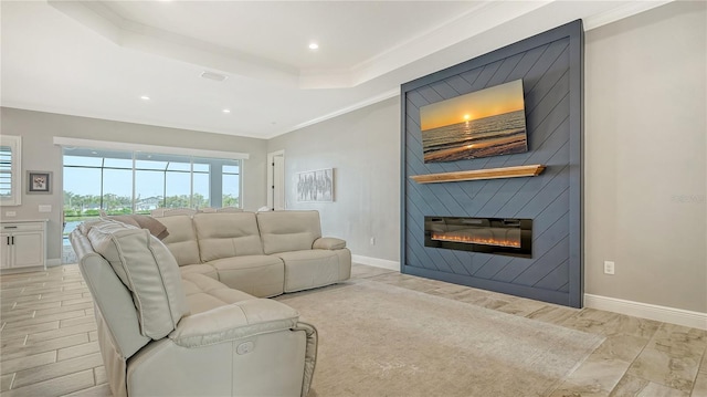 living room with visible vents, a large fireplace, baseboards, a tray ceiling, and ornamental molding