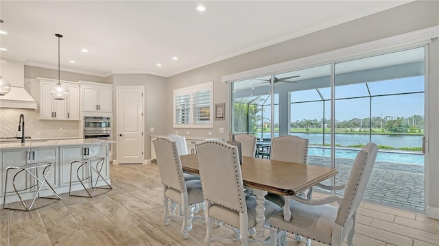 dining area featuring crown molding, baseboards, a water view, recessed lighting, and a ceiling fan