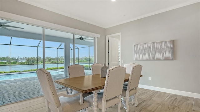 dining space featuring a ceiling fan, baseboards, wood finish floors, a sunroom, and a water view