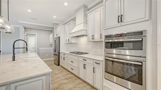 kitchen featuring a sink, tasteful backsplash, stainless steel appliances, crown molding, and custom exhaust hood