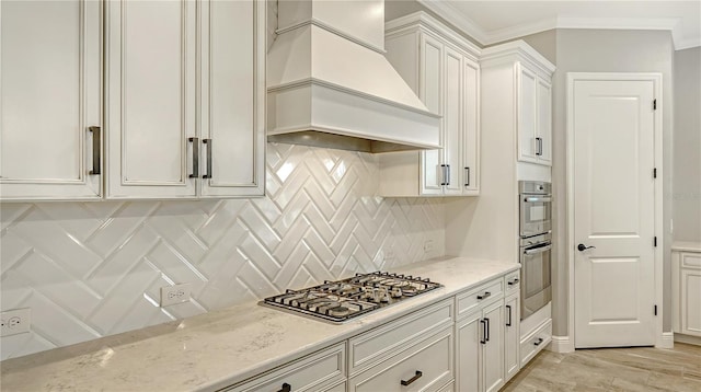 kitchen with stainless steel gas cooktop, light stone counters, decorative backsplash, custom exhaust hood, and white cabinetry