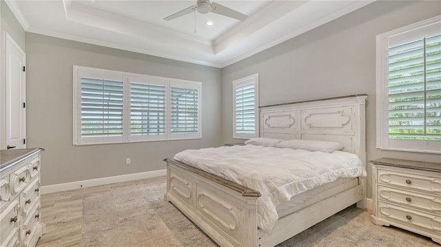 bedroom featuring a tray ceiling, baseboards, a ceiling fan, and crown molding