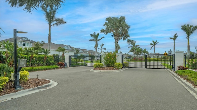 view of street featuring a gate, curbs, a residential view, and a gated entry