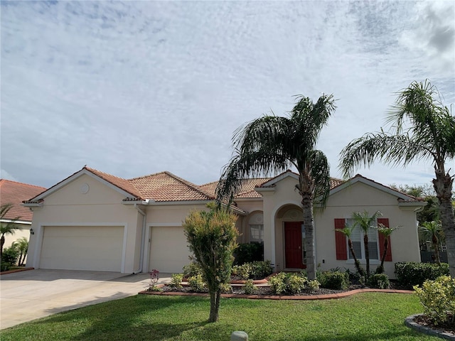 mediterranean / spanish-style house with stucco siding, a front lawn, concrete driveway, an attached garage, and a tiled roof