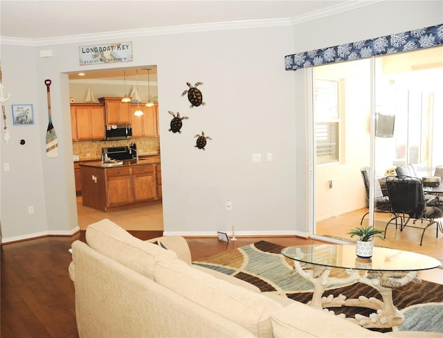 living area with baseboards, crown molding, and light wood finished floors