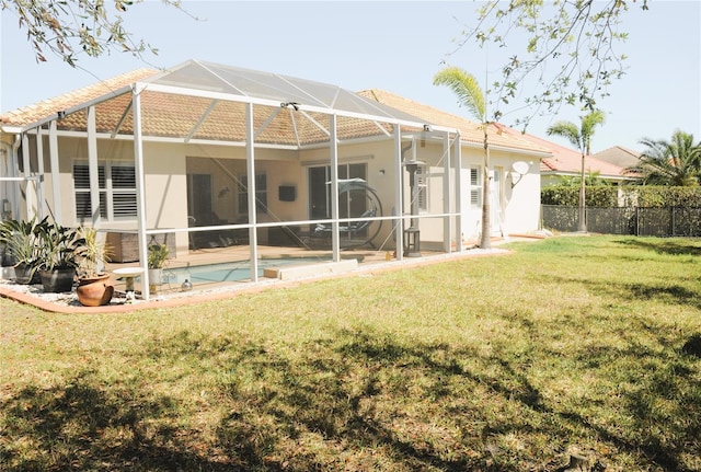 back of property with glass enclosure, a yard, fence, and stucco siding