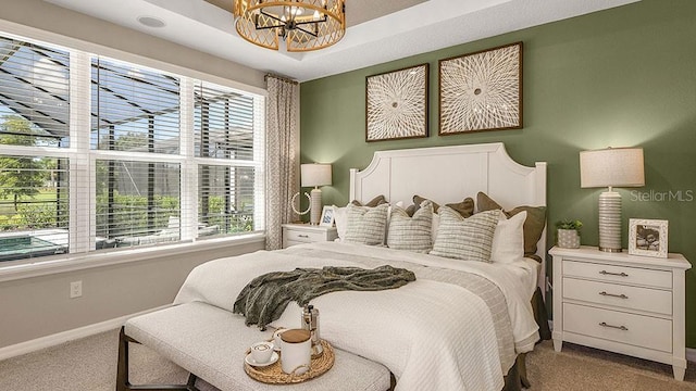 bedroom with carpet, a raised ceiling, baseboards, and an inviting chandelier