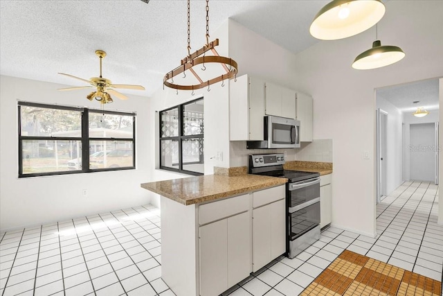 kitchen with stainless steel appliances, a healthy amount of sunlight, light tile patterned flooring, and a textured ceiling