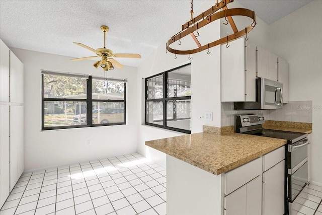 kitchen featuring light tile patterned floors, a textured ceiling, stainless steel appliances, a ceiling fan, and decorative backsplash