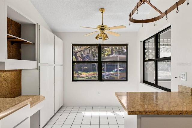 kitchen featuring a textured ceiling, light tile patterned floors, white cabinetry, a ceiling fan, and open shelves