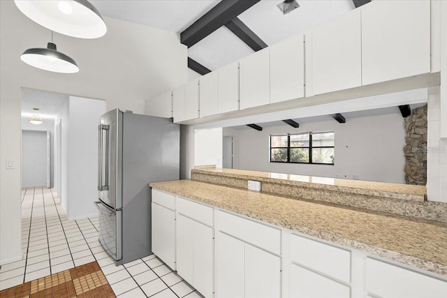 kitchen with vaulted ceiling with beams, light tile patterned floors, light countertops, and freestanding refrigerator