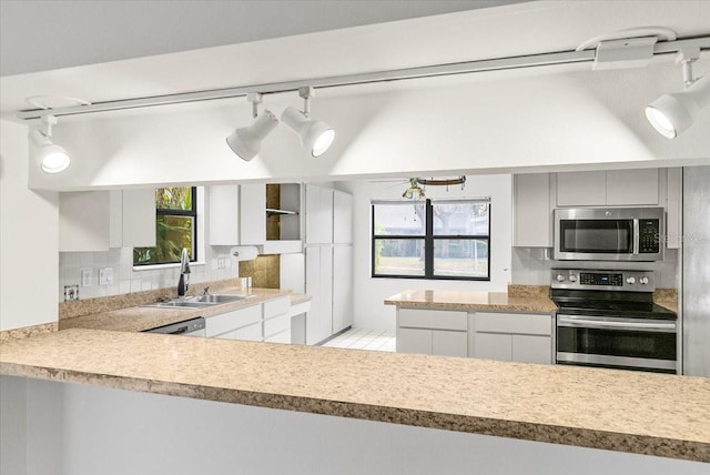 kitchen featuring light countertops, appliances with stainless steel finishes, a sink, and tasteful backsplash