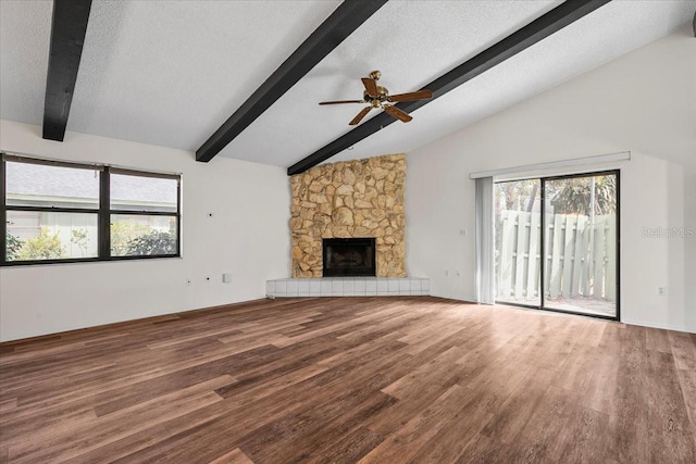 unfurnished living room with a textured ceiling, lofted ceiling with beams, a fireplace, and wood finished floors