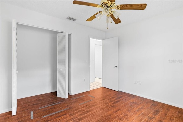 unfurnished bedroom featuring visible vents, a closet, hardwood / wood-style flooring, and a ceiling fan