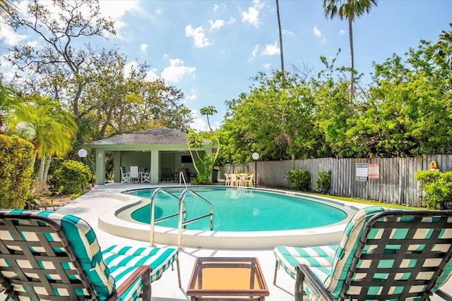 community pool with fence and a patio