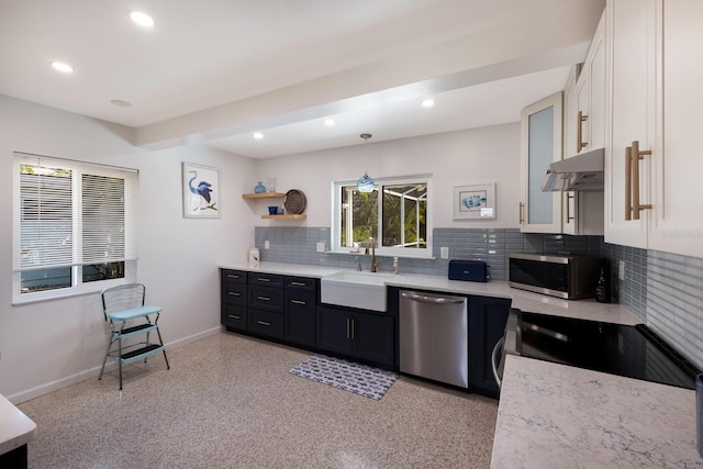 kitchen with baseboards, under cabinet range hood, stainless steel appliances, white cabinetry, and a sink