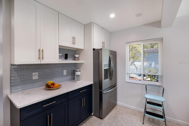 kitchen featuring backsplash, baseboards, stainless steel refrigerator with ice dispenser, light speckled floor, and open shelves