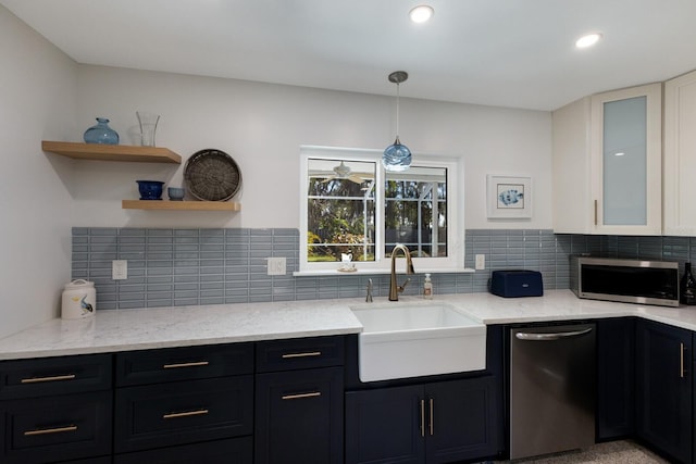 kitchen featuring light stone countertops, open shelves, a sink, stainless steel appliances, and dark cabinets