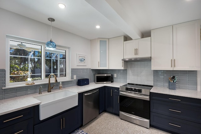 kitchen with a sink, under cabinet range hood, white cabinetry, stainless steel appliances, and light stone countertops