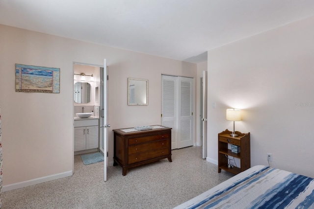 bedroom featuring ensuite bath, baseboards, a closet, and a sink