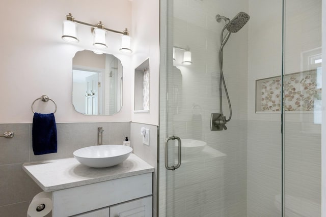 bathroom featuring vanity, a shower stall, and tile walls