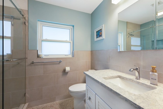 bathroom with vanity, a shower stall, toilet, and tile walls